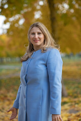 Young beautiful blonde girl in an autumn park in the maple leaves.
