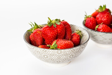 Strawberries in round plates, arranged on a white background.