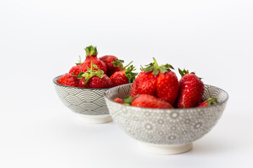 Strawberries in round plates, arranged on a white background.