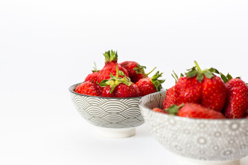 Strawberries in round plates, arranged on a white background.