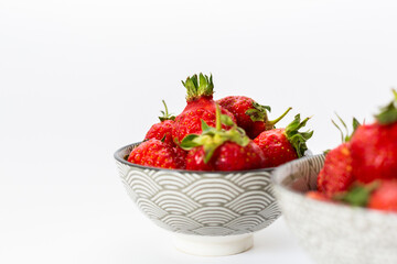 Strawberries in round plates, arranged on a white background.