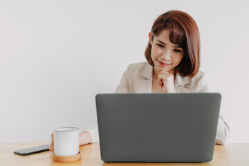 Pretty happy Asian working woman is working on her laptop in the office.