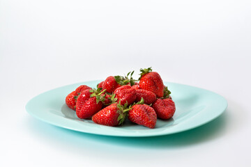 Red strawberries on a plate. Isolated on a white background.
