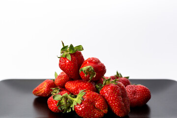 Strawberries in a black plate. Isolated on a white background.