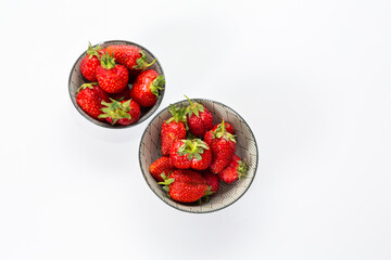 Strawberries in round plates, arranged on a white background.