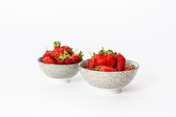 Strawberries in round plates, arranged on a white background.