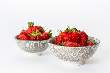 Strawberries in round plates, arranged on a white background.