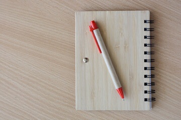 Notepad and pen prepared for notes. On a wooden background, close-up view from above
