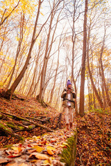 Naklejka na ściany i meble Active woman taking a walk through the forest on sunny autumn day