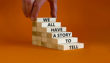 We all have a story to tell symbol. Wooden blocks with words 'We all have a story to tell'. Businessman hand. Beautiful orange background. Business, popular quotation concept. Copy space.