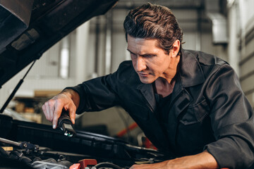 Waist up portrait view of the auto mechanic man with lamp working at the workshop. Car service, repair and people concept