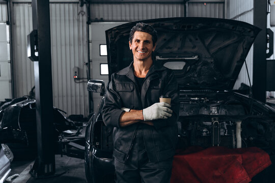 Waist up portrait view of the auto mechanic standing near opened car outdoors and holding wrench. Car repair concept