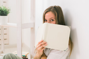 Girl covers her face with book. Literature, reading and knowledge concept.