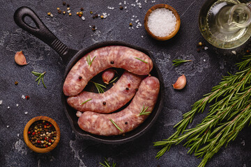 Raw sausages and ingredients for cooking on a black stone table.