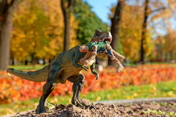 Fototapeta na wymiar Tyrannosaurus Rex attacked by security man. Miniature plastic figures. Soft focus effect