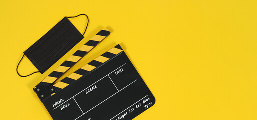 Clapper board or movie slate and black face mask on yellow blackground. Yellow and black color.