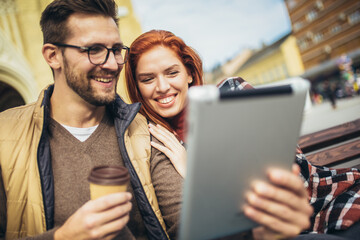 Trendy young couple in town using tablet