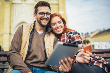 Trendy young couple in town using tablet and credit card.