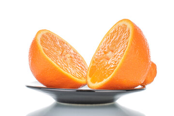 Two halves of organic ripe minneola on a ceramic dish, close-up, isolated on white.