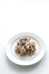 Braised pork on a white plate with bay leaves, white background
