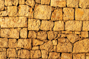 Full frame photo of old stone wall in the light of the evening sun. Antique stone wall background.