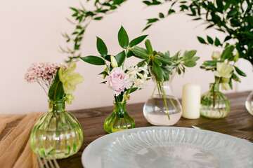 Many glass vases with flowers in the setting of the festive table. Selective Focus