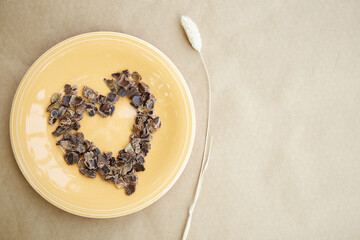 Carob - plant-based alternative - natural product on the plate a shape of heart with dry Lagurus ovatus grass. Organic antioxidants and protein. Top view.