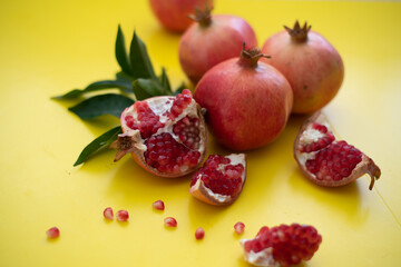 Three large, juicy and ripe pomegranates and  cut pomegranate on yellow background. Fruits contain many vitamins. healthy fruits:  good for healthy lifestyle.  food for diet. jewish holiday. Close up.