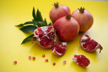 Three large, juicy and ripe pomegranates and cut pomegranate on yellow background. Fruits contain many vitamins. healthy fruits:  good for healthy lifestyle.  food for diet. jewish holiday. Close up.