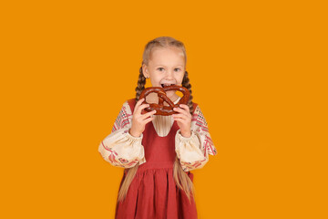 a beautiful little blonde girl in a national Slavic costume holds bread in her hands yellow background