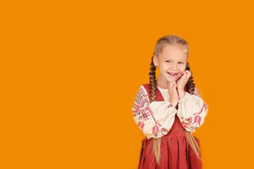 a little beautiful blonde girl in a national Slavic costume yellow background