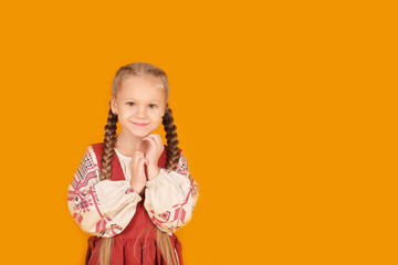 a little beautiful blonde girl in a national Slavic costume yellow background