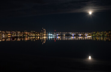 Fototapeta na wymiar Jyväskylä city at night and full moon reflections on lake Jyväsjärvi. Finland.