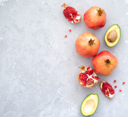 Many pomegranate and avocado on gray background. Fruits contain many vitamins. Fresh fruits:  good for healthy lifestyle.  food for diet. top view. Place for text.