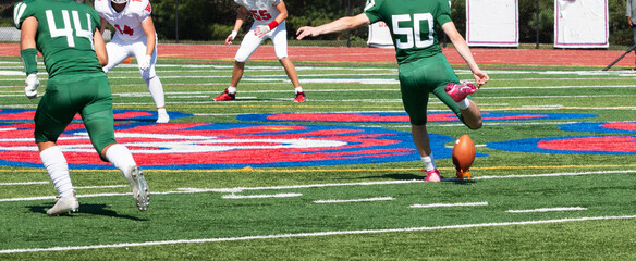 Football kicker kicking the ball on a tee