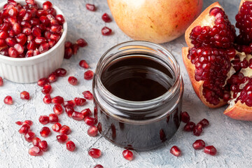 Glass bottle of pomegranate sour sauce with fresh ripe whole and split pomegranate fruit (Turkish name; nar eksisi)