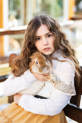 country girl sitting on a bench with a rabbit in her hands