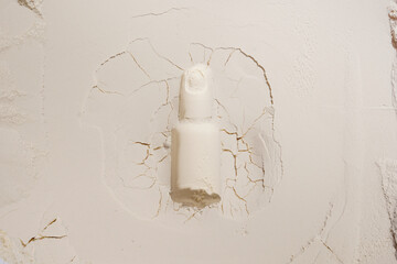 cosmetic bottle oil from sand on white textured background with cracks