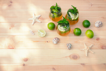 Mojito cocktail with lime and mint on wooden table. Starfishes and seashells near.