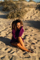 Fototapeta na wymiar Chica con sudadera y pelo rizado en la playa al atardecer