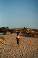 Chica delgada morena con aparatos en la playa al atardecer