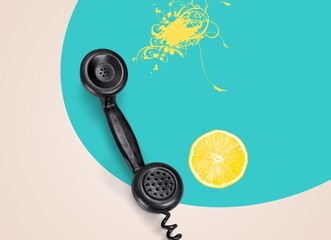 Splash of juicy lemon. Composition with citrus and retro, vintage phone on abstract background.