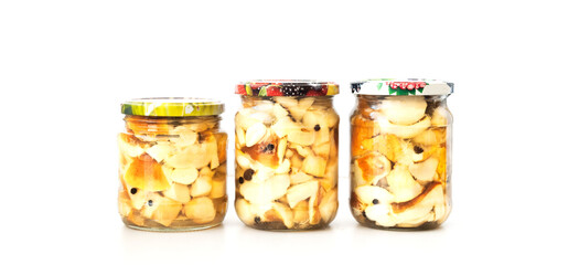 Preserved mushrooms in glass jars on a white background. Preparation of products for long-term storage. Close-up