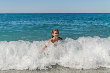 Little happy adorable girl child swims in the sea and plays on the waves during the holidays on the sea coast