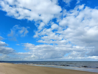 Gentle waves on the shore of the Baltic Sea and many white fluffy clouds on the sky