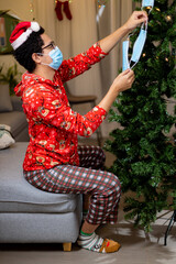 Obraz premium latin man decorating a tree wearing surgical mask