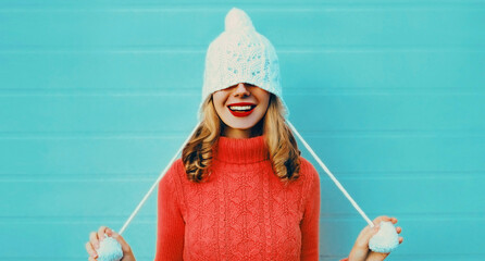 Winter portrait of happy smiling young woman wearing a knitted sweater, white hat having fun on...
