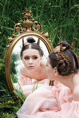 a girl in the image of a snail looks in the mirror and holds a snail on her head