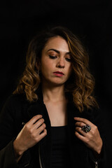Dramatic portrait of confident young latin woman with long hair looking down on black background