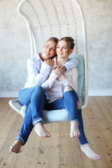 mature motherand daughter hugging each other in armchair.